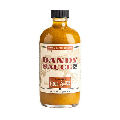 A bottle of Dandy Sauce Co. Original Gold Sauce with a beige label and black cap.