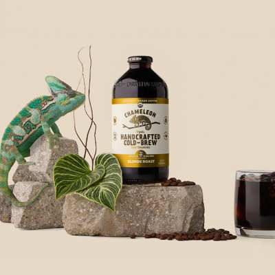 A bottle of Chameleon Handcrafted Cold-Brew Coffee with a yellow label and a chameleon next to it.