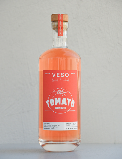 A clear bottle with a red label featuring the text 'Veso Tomato Vermouth' and a cork stopper.