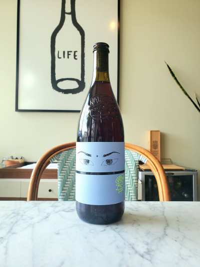 A bottle of Niepoort Nat Cool Drink Me Rojo with a minimalist design featuring a light blue label and playful illustrations.