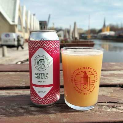 A can of Laughing Monk Brewing Sister Merry Hazy IPA next to a glass of the beer, featuring a red and white patterned design.